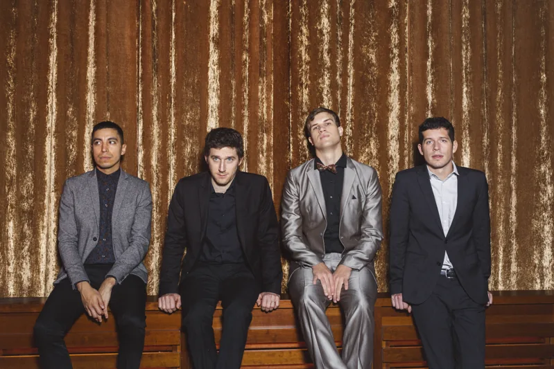 Die vier Musiker vor einem goldenen Kinovorhang